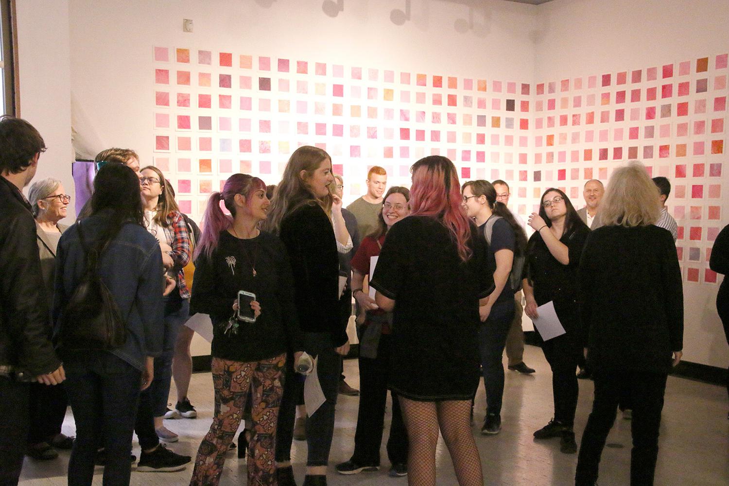 Students and visitors at a Spring 2019 Senior Thesis Opening. (in the background, paintings by Ha...