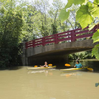 Students kayak along the Pike River under Carthage?s red bridge.